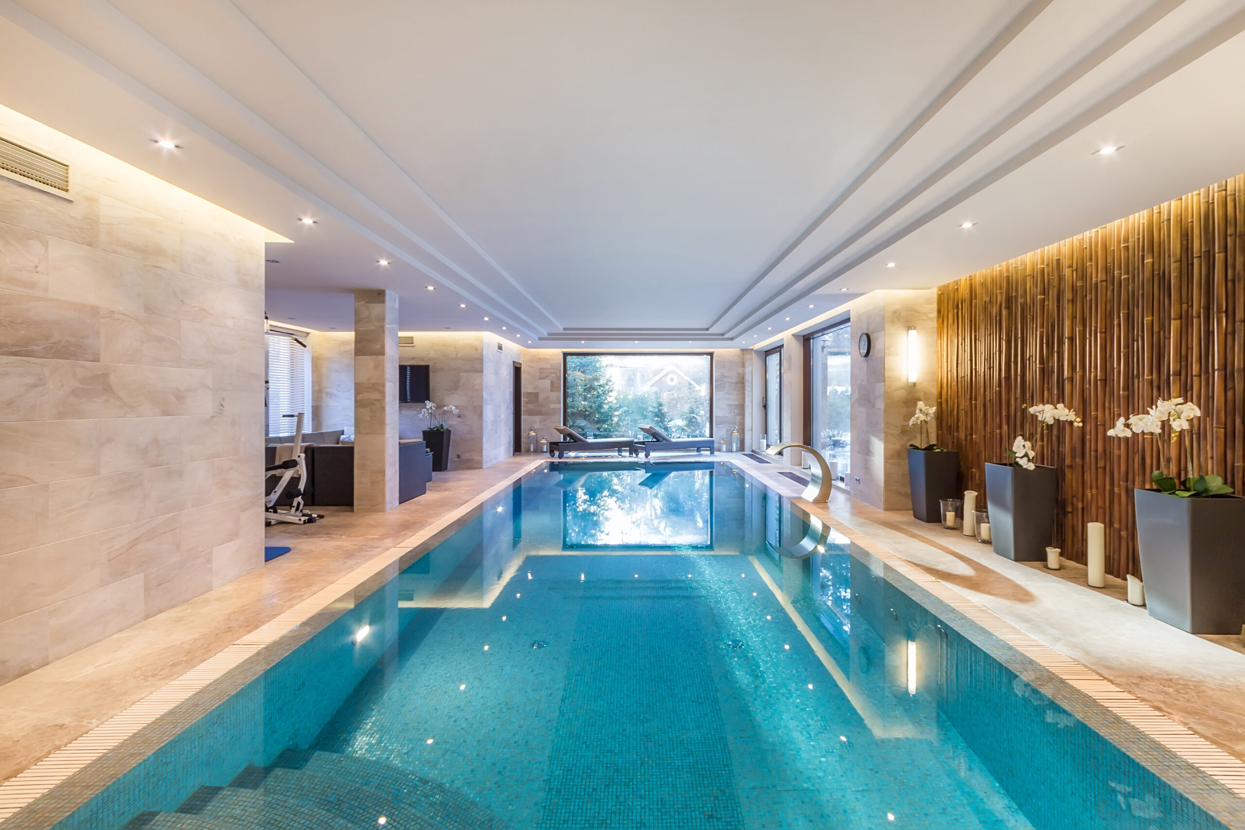 Luxurious indoor pool with stone walls, bamboo accents, and modern lounge seating